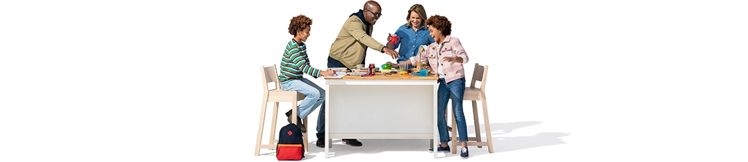 A family of four has fun multi-tasking at the kitchen table.